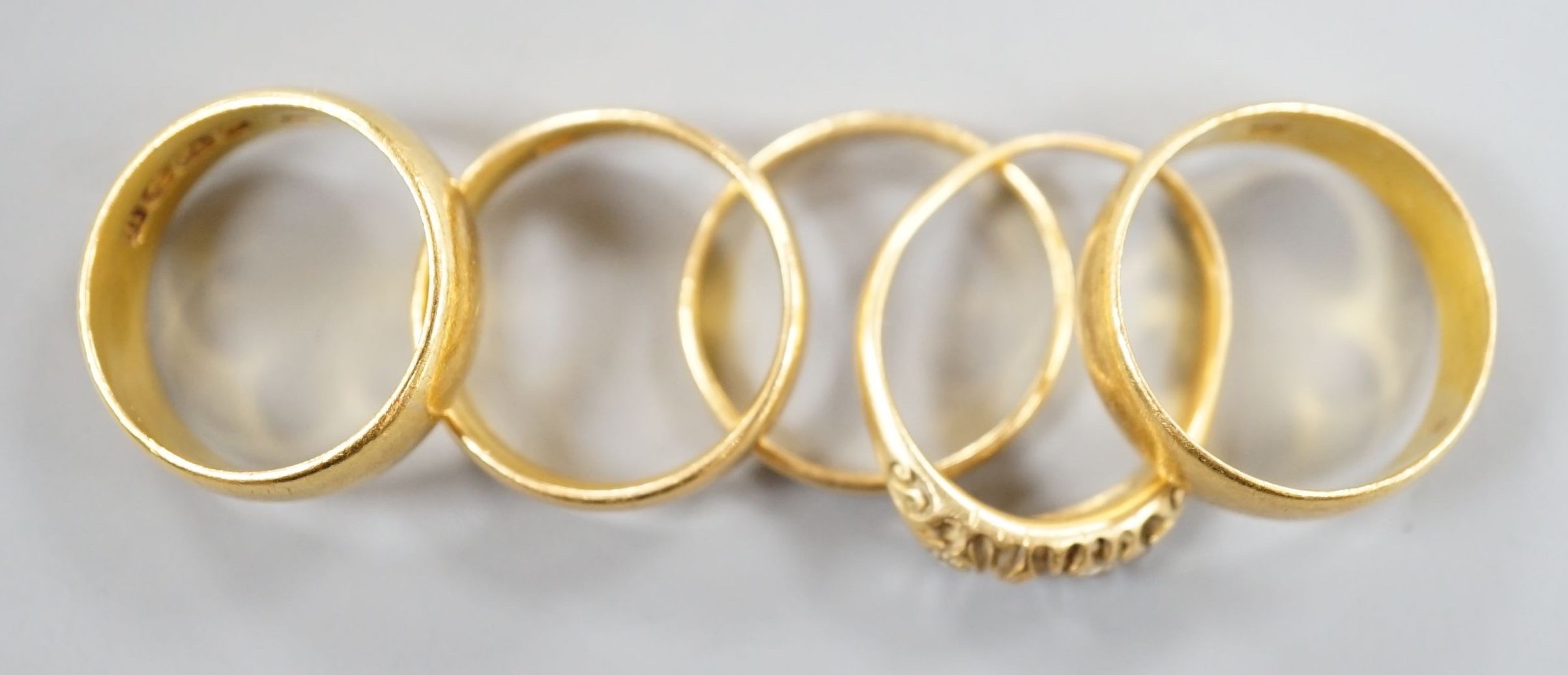 Four assorted mainly early 20th century 22ct gold wedding bands and an 18ct and diamond chip set ring(stones missing